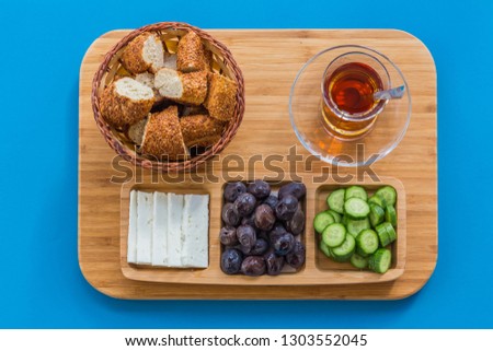 Typical Turkish breakfast of simit, cucumber, olives, and cheese, with Turkish tea, served in a glass.