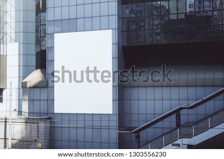 Empty white billboard on glass building. Advertisement, ad and commercial concept. Mock up 