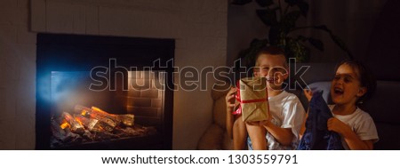 Little boy receiving a giftbox with red ribbon. Girl sitting beside