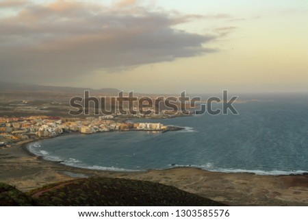 The red mountain beach and "El Médano" town in the south coast of the Tenerife Island, Spain. Picture taken at sunset from the red mountain.