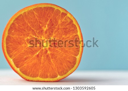 half fresh juicy orange on a blue background in minimalism style. vacation symbol. close-up image