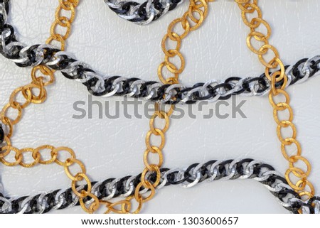 Silver and gold color chains. Chains on white leather background