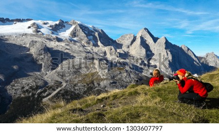 Two young women tourists taking picture of mountain landscape.  Marmolada Glacier. Dolomiti, Itay. Alps.