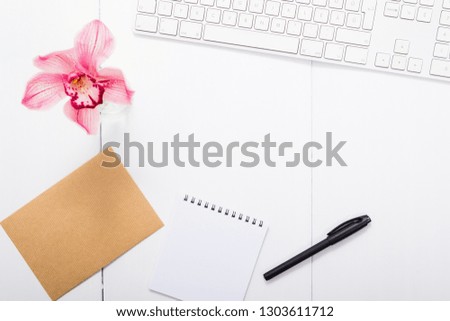 place of work with pink orchid flower, keyboard, brown papers, checklist, black pen, top view
