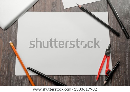 Empty paper sheet, pencils, bow compass and tablet computer on wooden table, top view. Mockup for your art project.
