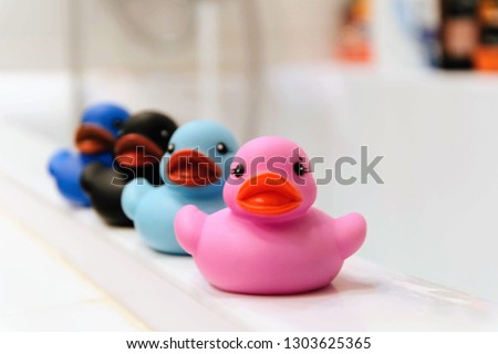 Colorful rubber ducks in the bathroom. A set of rubber ducks sitting in a row on the edge of the bath
