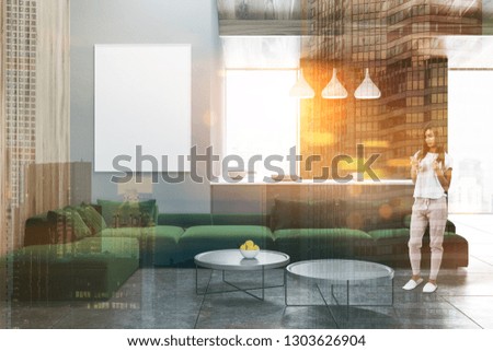 Young woman standing in stylish living room with gray walls, tiled floor, long green sofa and two round coffee tables. Vertical poster. Toned image double exposure mock up