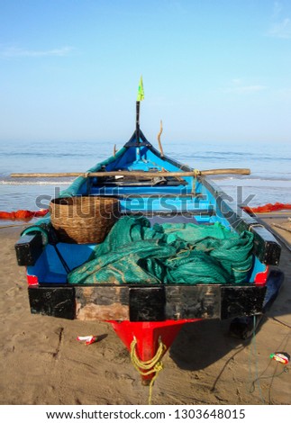 Fishing boat stands on the sand by ocean. Vertical picture