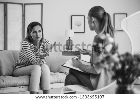 Young beautiful woman sitting on the couch in therapist office, black and white photo