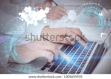 Hands of business people working with laptop in office and writing with double exposure of business infographics and hud. Toned image. Elements of this image furnished by NASA