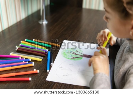 A student of Junior classes sitting at home at the table doing homework on drawing