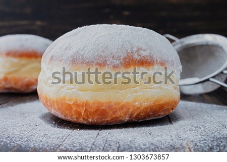 Freshly made doughnuts, heavily covered in powdered sugar on a an old wooden table