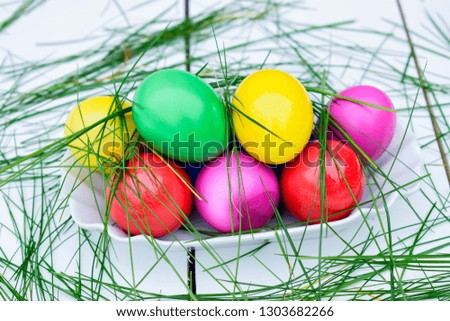 Pastel and colorful Easter eggs on a white plate with green grass.