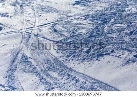 Traces of skiers on white snow in the mountains .