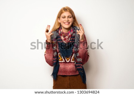 Hippie woman over white wall with fingers crossing and wishing the best