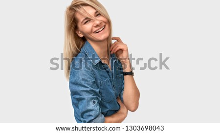 Horizontal closeup portrait of happy blonde european woman smiling broadly standing in blue denim shirt over white background. Business female posing on studio wall with copy space for your promotion