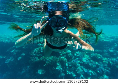 Young woman snorkeling making peace signs underwater
