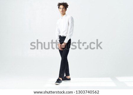 guy with curly hair in full growth on a light background                         