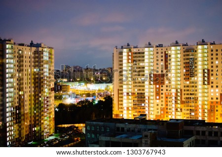 Night city view. Multi-storey apartment buildings with luminous windows against a dark sky.