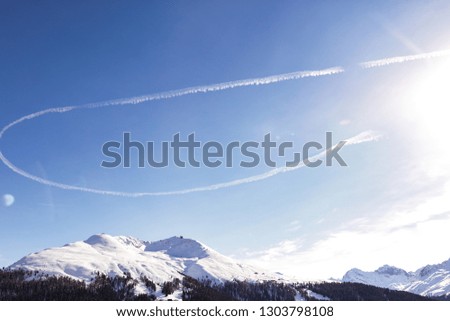 Picture of the peaceful nature, pure blue sky and sun shining. High mountain peaks covered with white snow. Winter trip to the Europe, Switzerland. Aircraft trail in the sky. Fresh cold air.