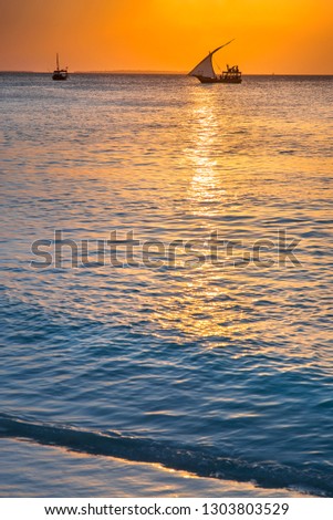 sail boat in orange sunset with calm sea in the evening in Zanzibar