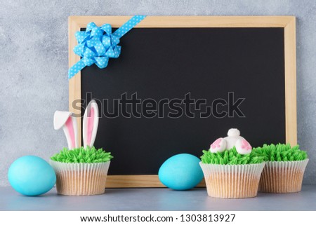 Easter chalkboard background with eggs and funny bunny butt and ears cupcakes. Space for text.
