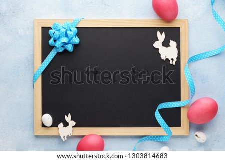 Empty chalkboard and easter decoration flat lay. Wooden bunny and pink eggs. Space for lettering.