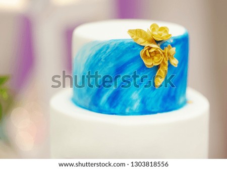 Elegant sweet table set wedding cake with blue cake with golden flowers and cupcakes on wedding or event party. Sweet table on wedding party.