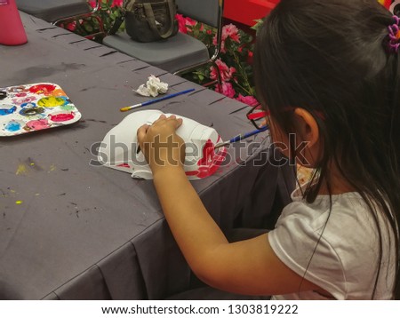 The girl is using a paintbrush painted on a face mask. Handicrafts kids activity. Fun training for kids. 