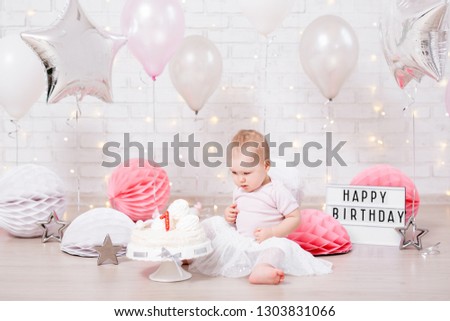 birthday party concept - funny little girl with cake over brick wall background with lights and balloons