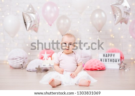 first birthday - cute little baby girl in birtday decorations with cake and balloons