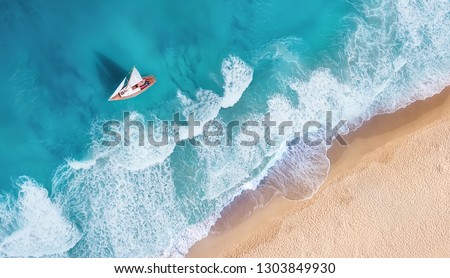 Waves and yacht from top view. Turquoise water background from top view. Summer seascape from air. Top view from drone. Travel-image Royalty-Free Stock Photo #1303849930