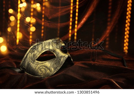 Photo of elegant and delicate gold venetian mask over dark velvet and silk background