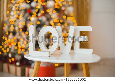Love. Large white wooden letters "love" on a blurred background of light bulbs. A gift for Valentine's Day. St. Valentine's Day. Background to desktop.