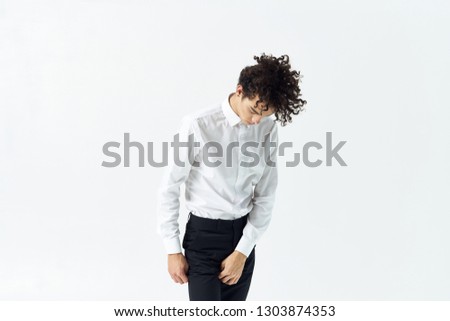 Cute elegant guy with curly hair in a white shirt in black pants office worker