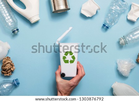 Hand holding a recycling garbage bin with lots of waste packaging Royalty-Free Stock Photo #1303876792