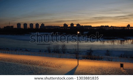 winter evening cityscape. beautiful view from the coast to the residential quarter across the river on the background of a fantastic sunset