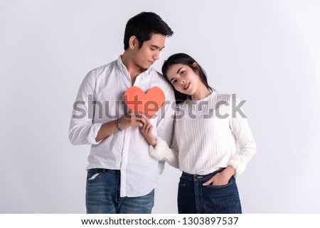 Beautiful Young couple at home,enjoy spend time together in celebration Saint Valentine's day,hand hold gift red heart paper cartoon together,happy and love motion.