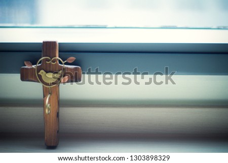 The wooden cross on the window with the morning light.