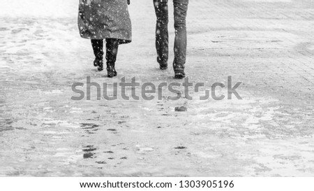 Winter City Slippery Sidewalk. Back view on the feet of people walking along the icy snowy pavement. Pair of shoe on icy road in winter. Abstract empty blank winter weather background