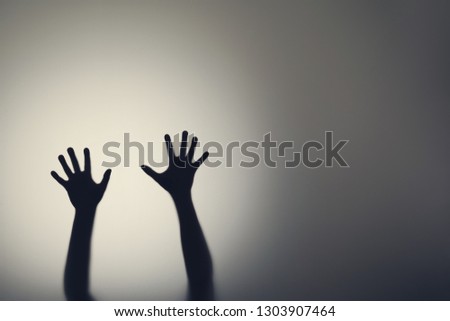 Dark silhouette of woman hands behind glass door. Concept of depression, fear, panic attacks