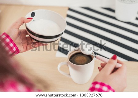 Pouring sugar on coffee cup. Woman adding sugar to her coffee 
