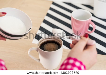 Pouring sugar on coffee cup. Woman adding sugar to her coffee 