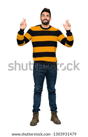 Full-length shot of Handsome man with striped sweater with fingers crossing and wishing the best on isolated white background