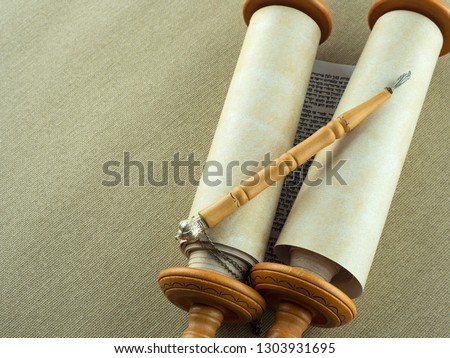 Torah Scrolls on wooden fasteners with a pointer on a rough canvas. Copy space. Royalty-Free Stock Photo #1303931695
