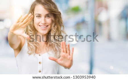 Beautiful young blonde woman over isolated background Smiling doing frame using hands palms and fingers, camera perspective