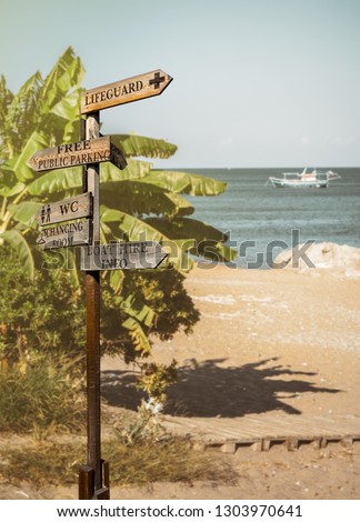 Beach sign boards for directions to toilets, parking, lifeguard, changing room and boat hire. Wooden pointers about the tourist information on the coast. Arrows on a signpost about resort services.