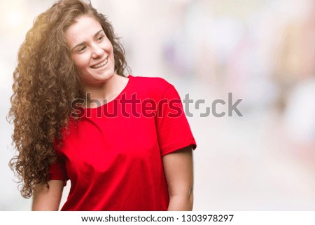 Beautiful brunette curly hair young girl wearing casual look over isolated background looking away to side with smile on face, natural expression. Laughing confident.