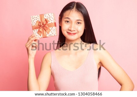 Young Asian woman with a gift box on pink background