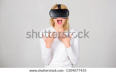 Excited smiling businesswoman wearing virtual reality glasses. Woman wearing virtual reality goggles in grey background. Funny young woman with VR. Virtual reality